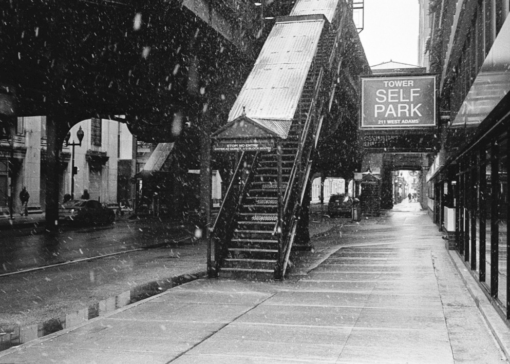 Snow falling beneath the elevated tracks beside a stairway on West Adams.